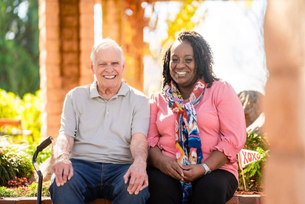 caregiver and elderly man sitting on bench together