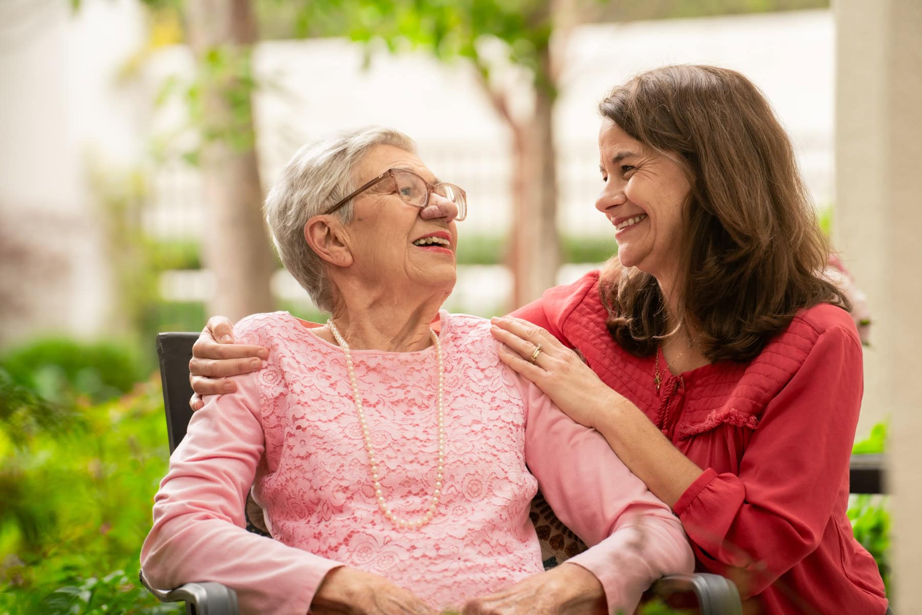 Elderly woman smiling at her daughter during a visit, symbolizing the connection and trust in long-distance caregiving.