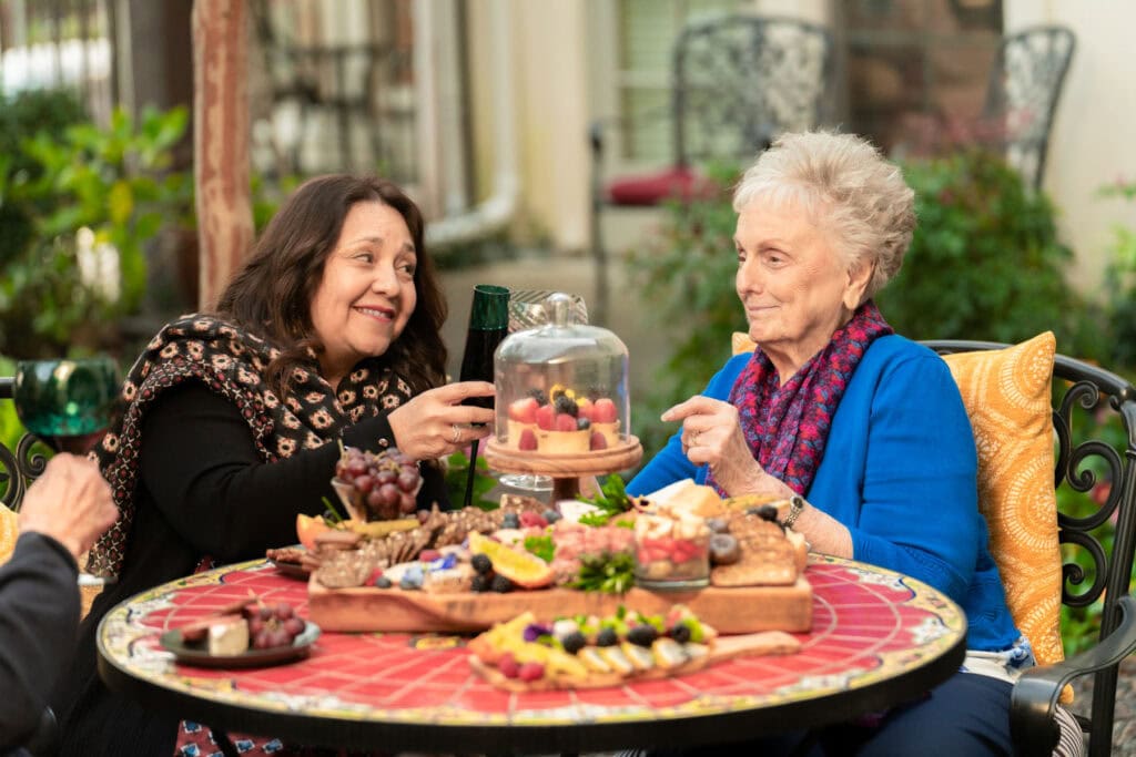 Younger woman having dinner with her older loved one, highlighting quality time and care while planning a vacation with a loved one who needs support.