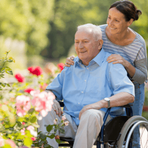 older gentleman on a wheelchair and his caregiver on the garden