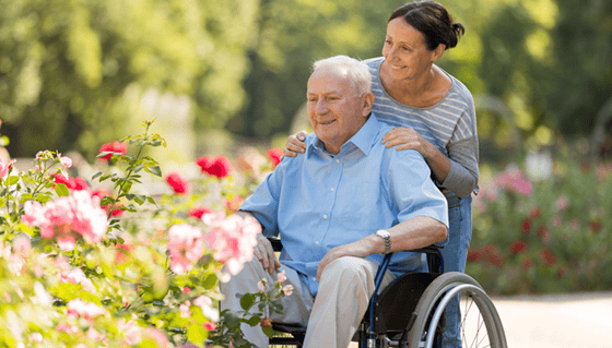 older gentleman on a wheelchair and his caregiver on the garden