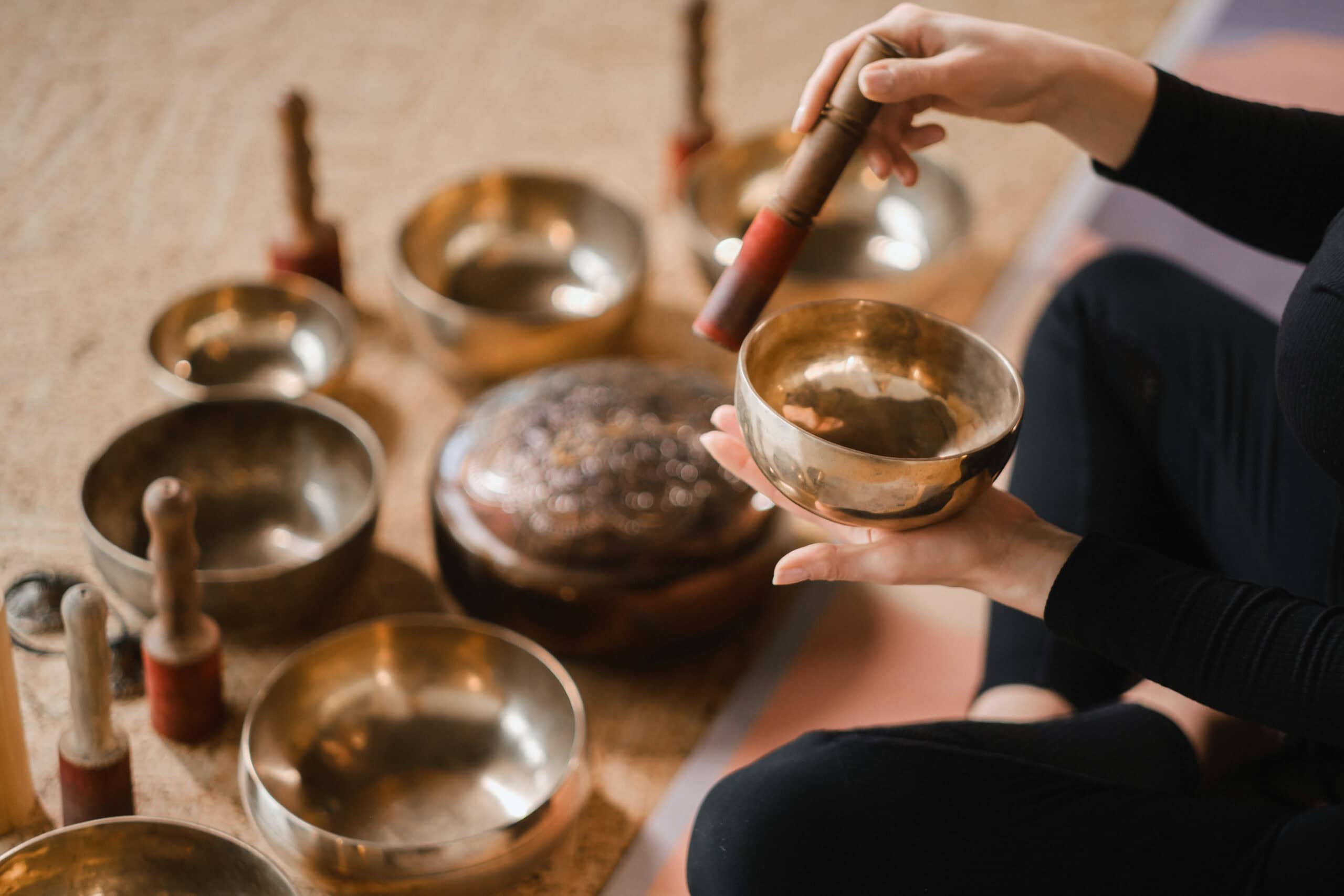 Close-up of a woman's hands sitting in a lotus position using a singing bowl indoors. Relaxation and meditation. Sound therapy, alternative medicine. Tibetan Bowls.