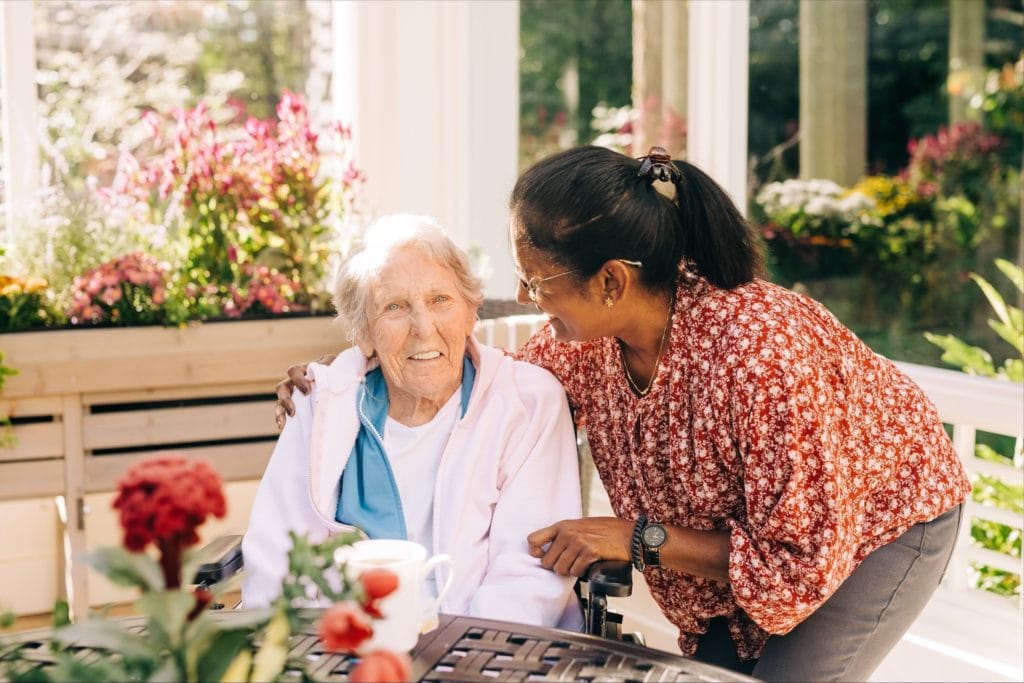 elderly woman and caregiver sitting in garden