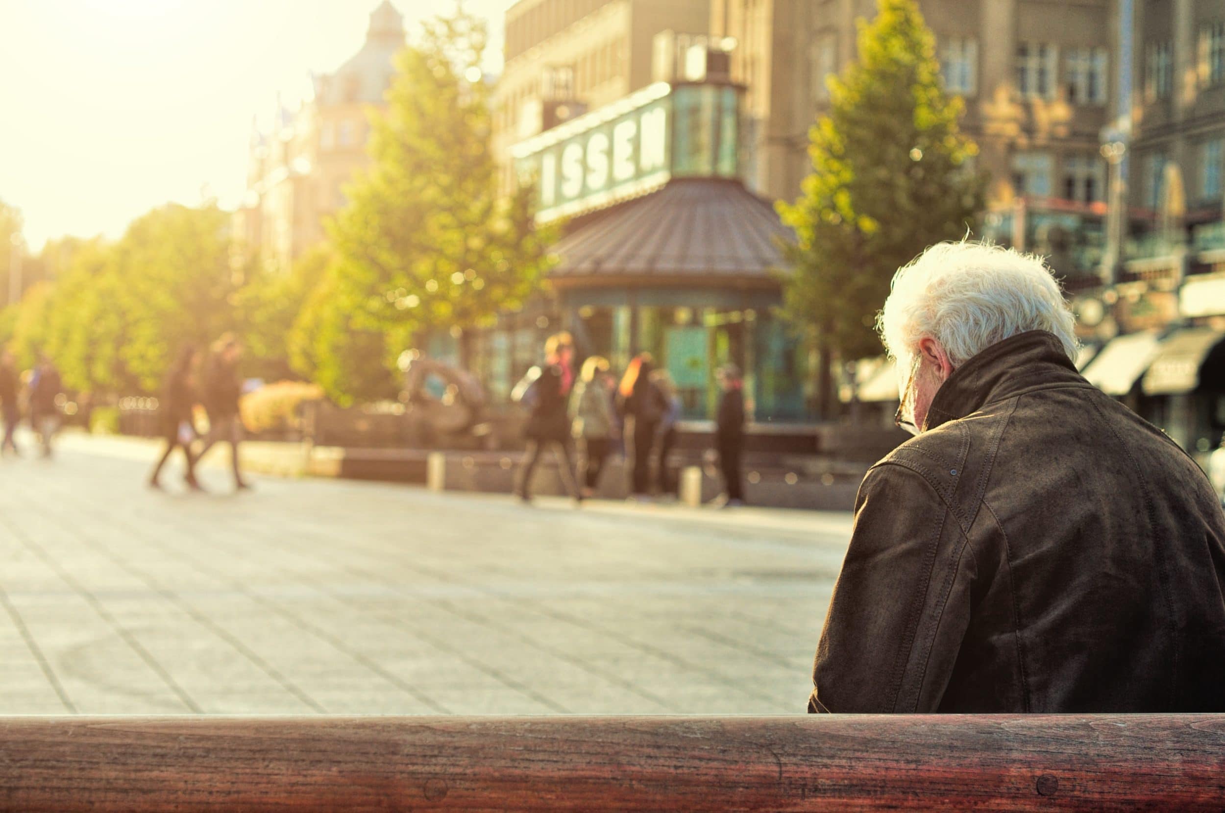 older adult senior affected by loneliness and depression at the holidays sits alone on bench