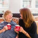 elderly woman and caregiver enjoying coffee