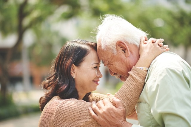 Daughter and senior father embrace with their heads touching