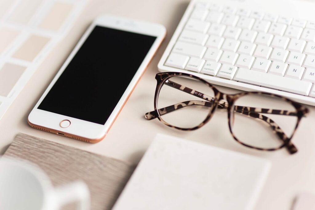 closeup of keyboard, phone, and glasses