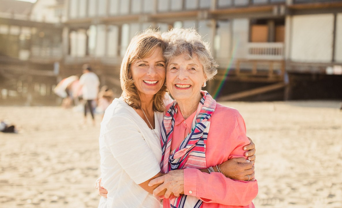 family member and resident hugging on beach