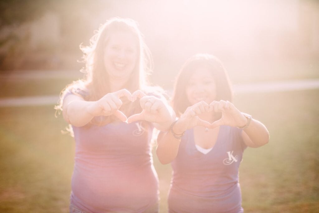 team members making hearts with their hands in the sun