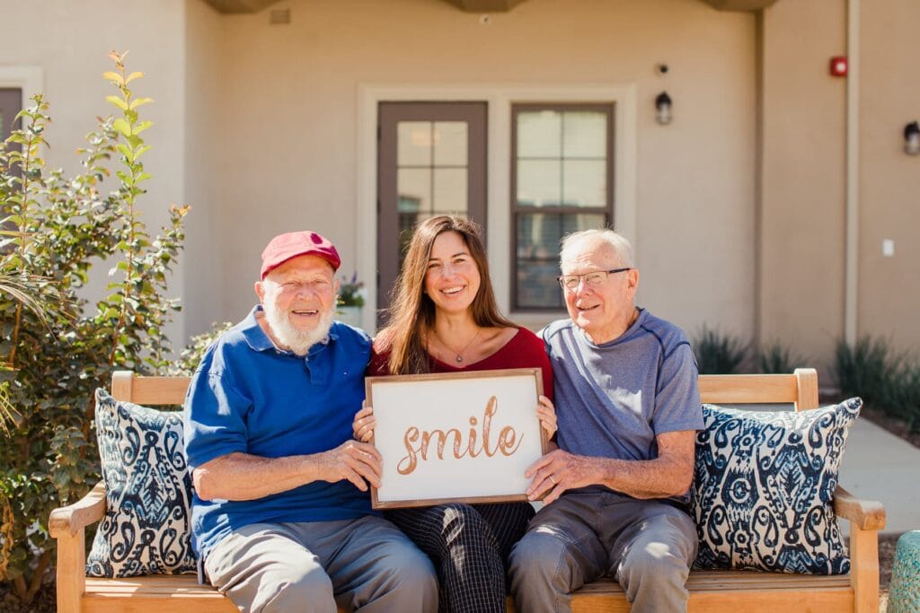 team member with two male residents holding sign that says 
