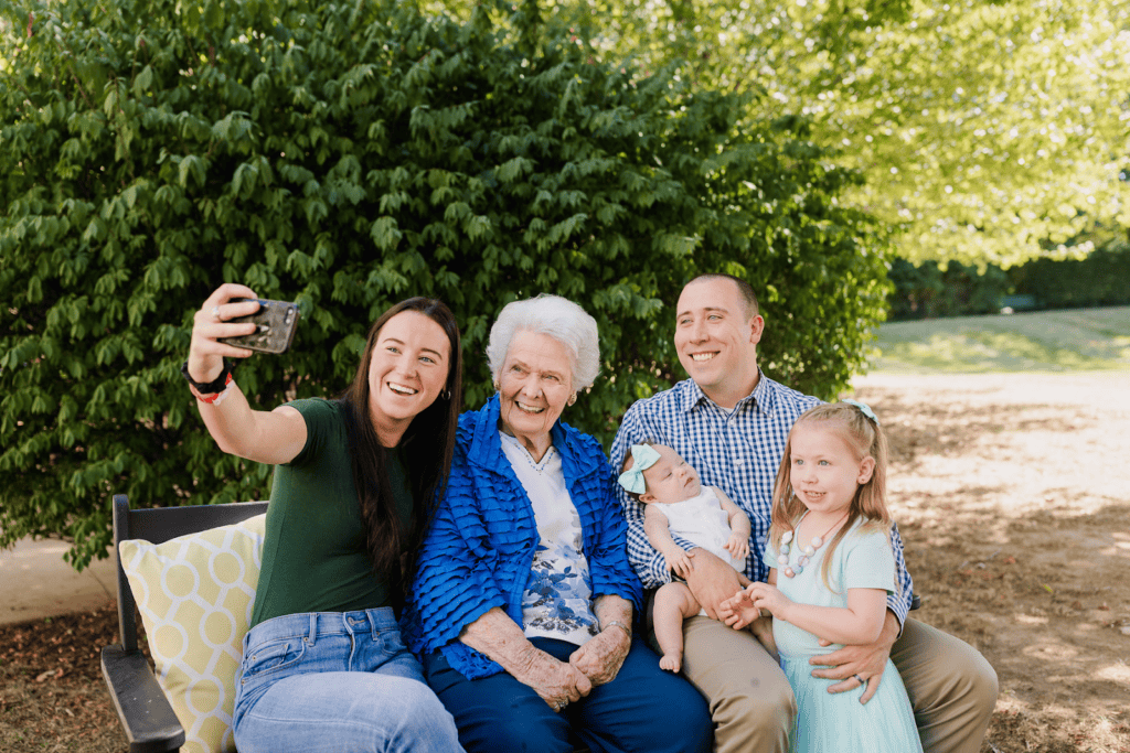 family posing for photo on phone with resident