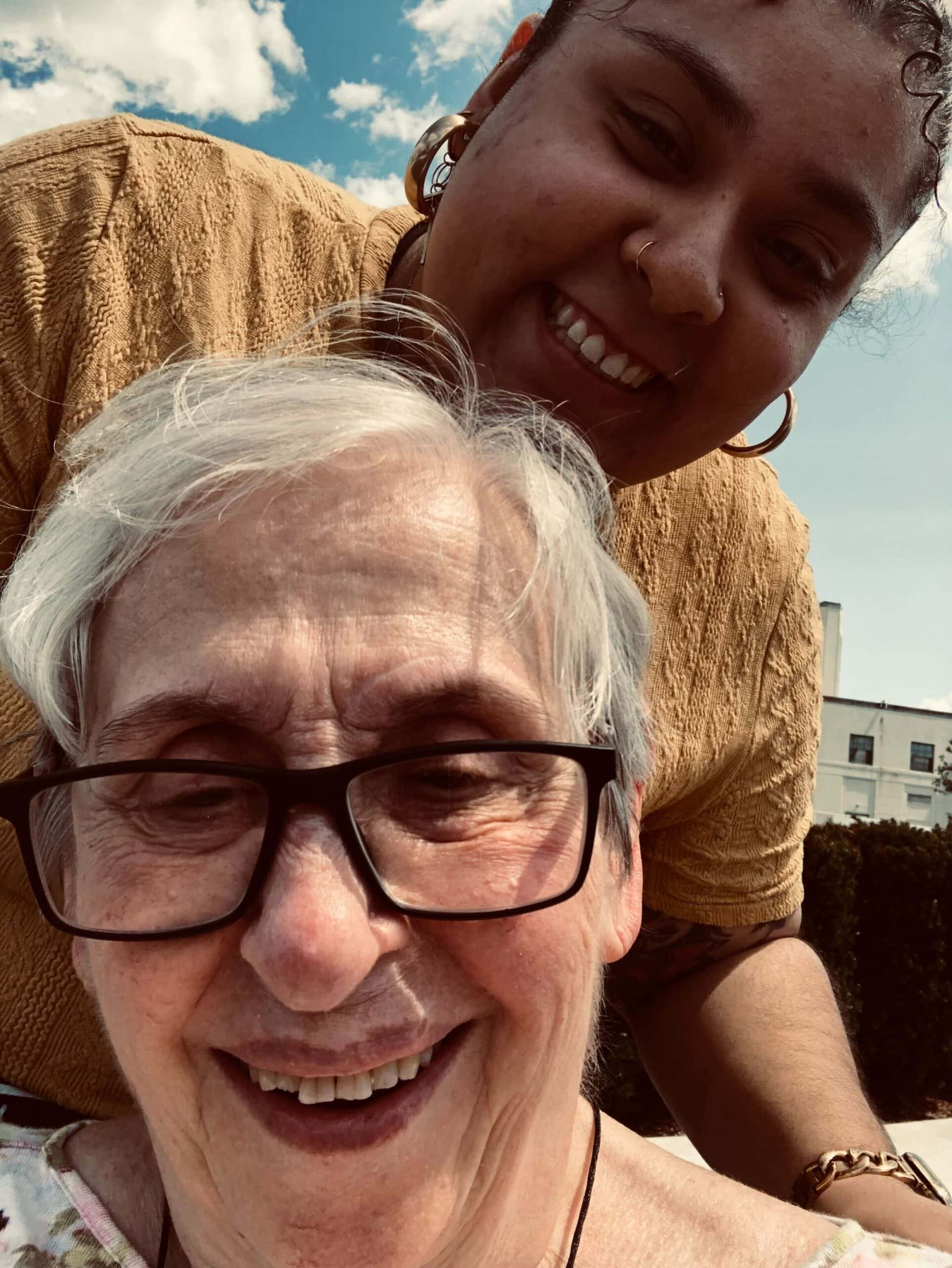 resident in chair with staff member looking over her shoulder outside